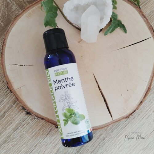 Flacon d’hydrolat de menthe poivrée bio sur fond vert avec feuilles de menthe fraîches