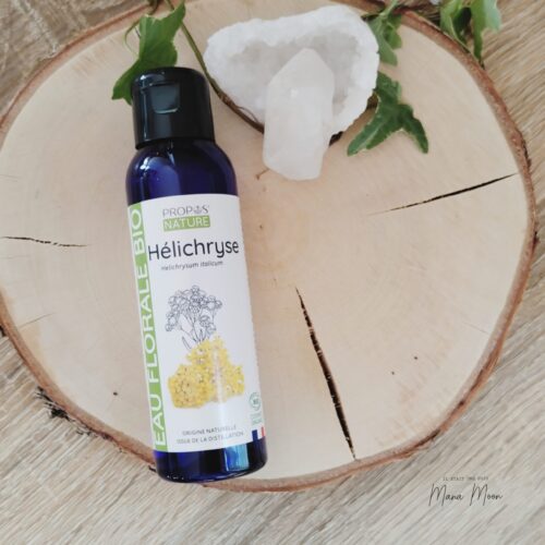 Flacon d’hydrolat d’Hélichryse bio posé sur une table en bois, entouré de fleurs séchées d’immortelle